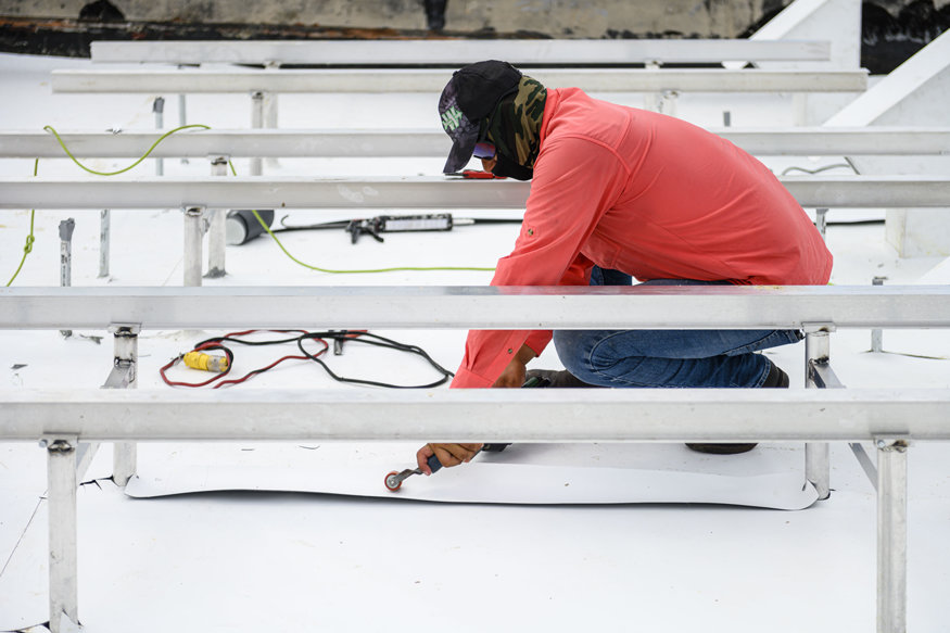 Crew adjusting membrane near roof amenities.