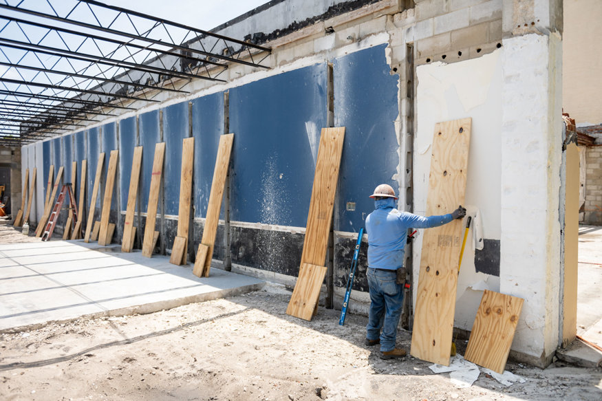 Worker positions plywood forms along exposed concrete masonry walls.