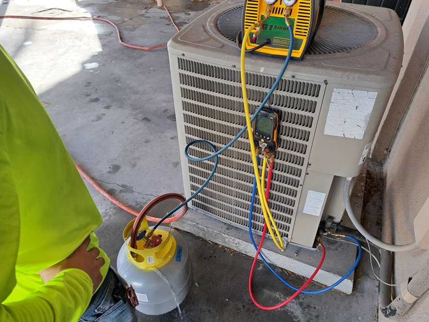 Worker handling refrigerant recovery unit outside of 645 Cleveland Street during HVAC system removal.