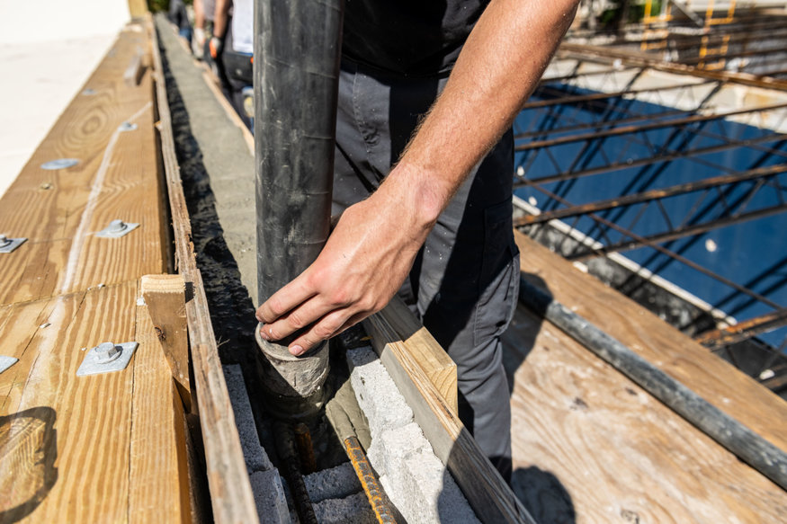 Worker directs concrete hose into parapet.