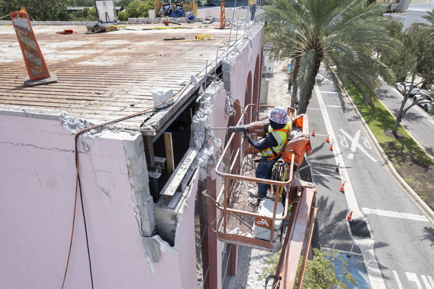 Worker removing façade and exposing steel beam.