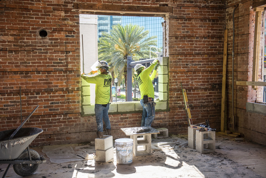 Masons rebuilding second-floor window openings with concrete blocks at Peoples Bank.