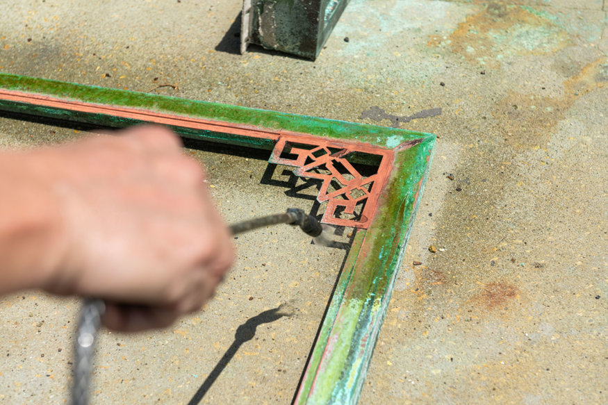 Specialist cleans decorative copper clock frame.