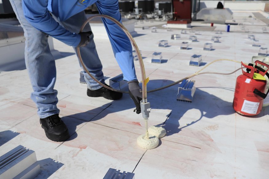 Applying foam adhesive to rooftop.