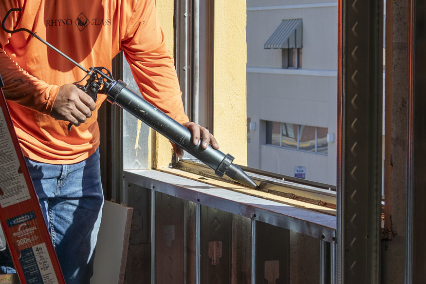 Worker applying caulk to window frame.
