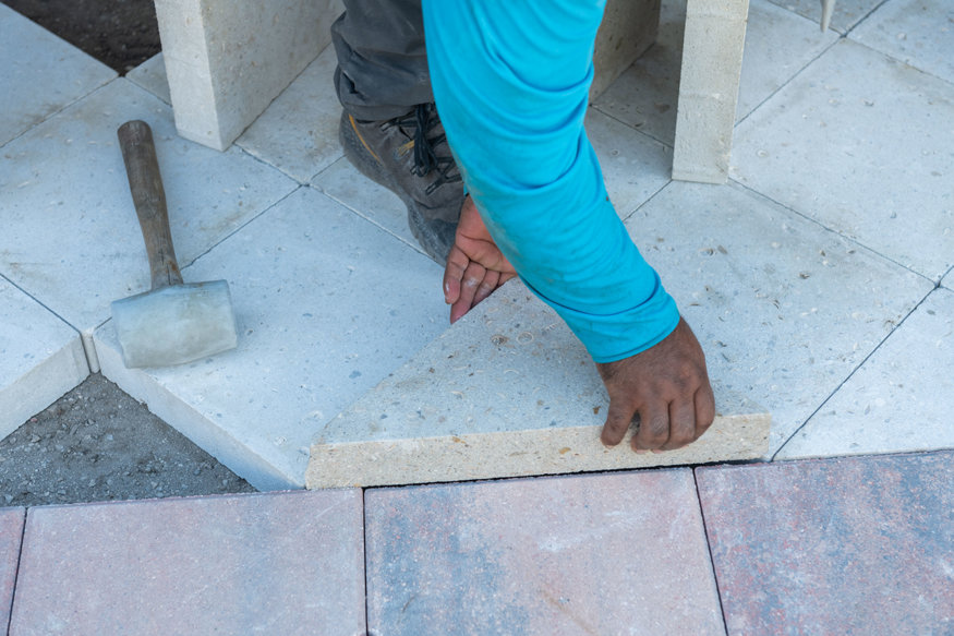 Worker aligns paver section.