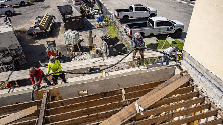 Workers guide grout hose during rear wall construction.