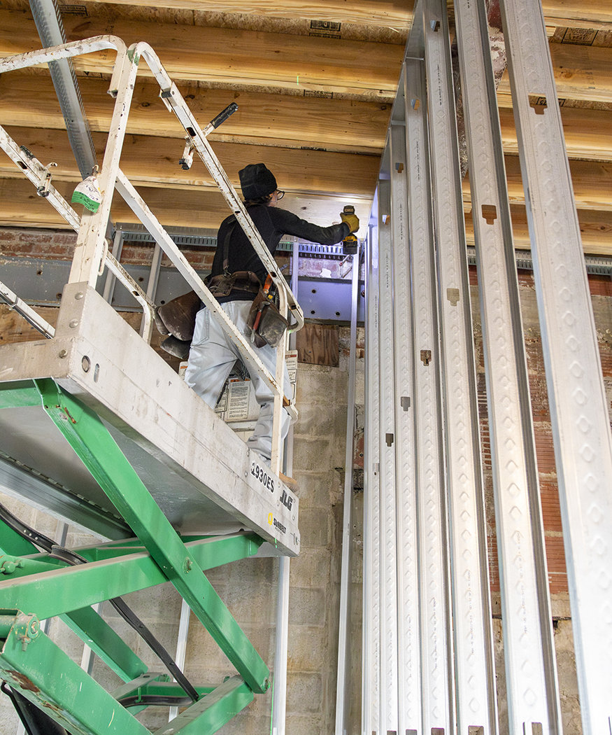 Worker on a lift installing vertical framing.