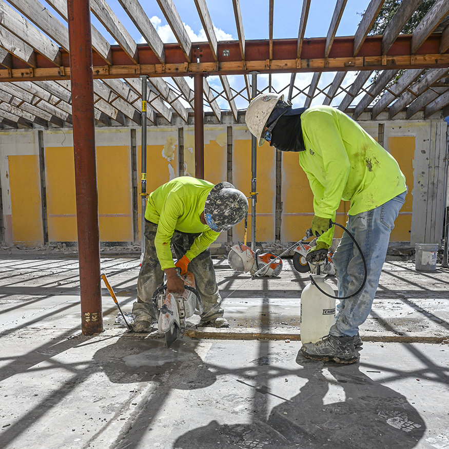 Workers cut concrete slab sections for removal.