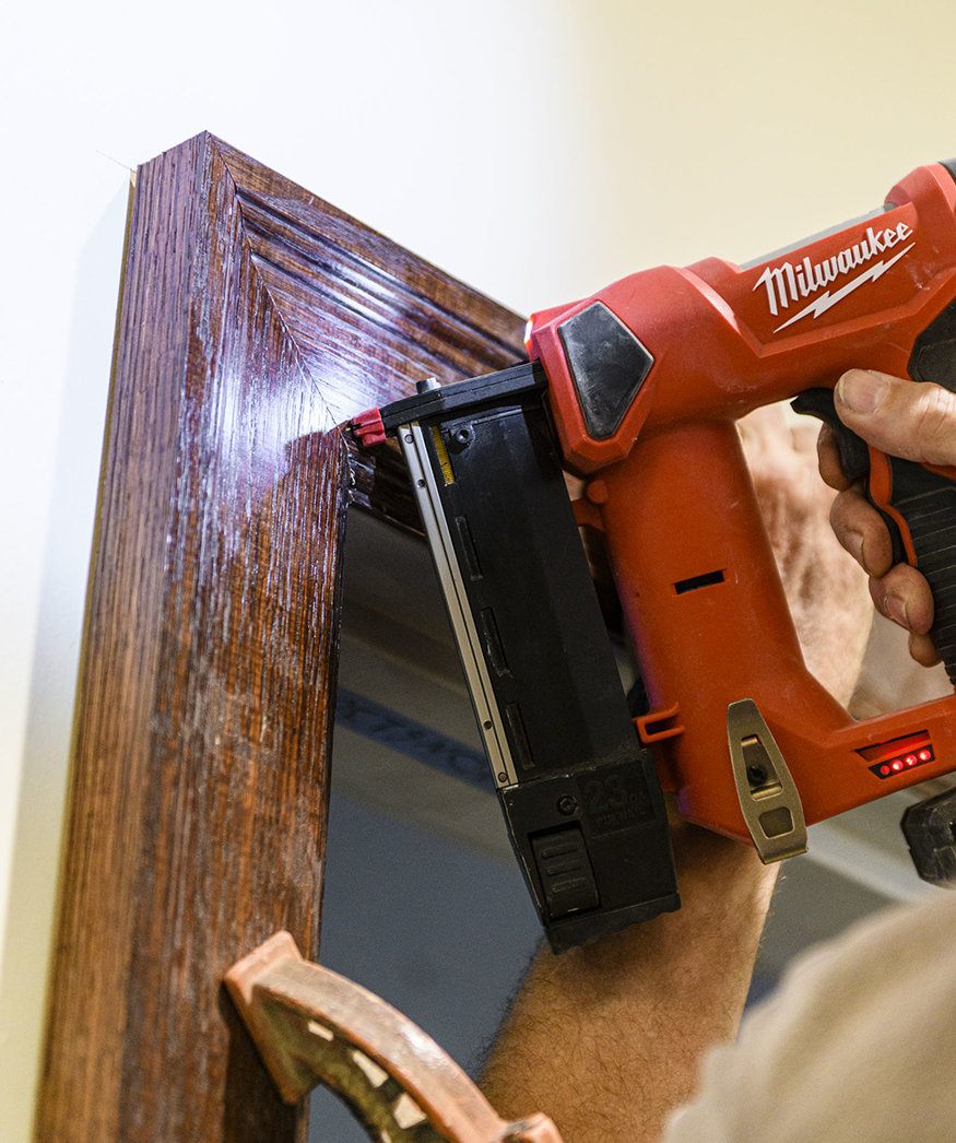 Workers securing trim in hallway.