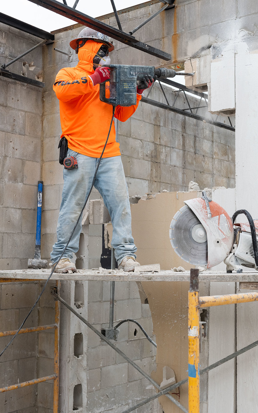 Worker uses demolition equipment to create new wall openings inside 629 Cleveland Street.