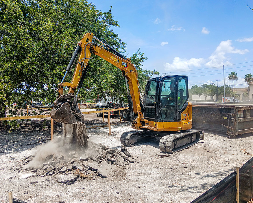 Excavator crushes concrete for removal and disposal.