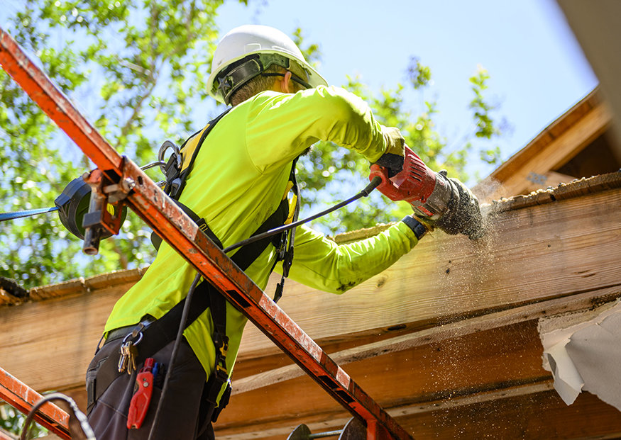 Close-up of a worker using a reciprocating saw to cut into the existing overhang at 623-627 Cleveland Street.