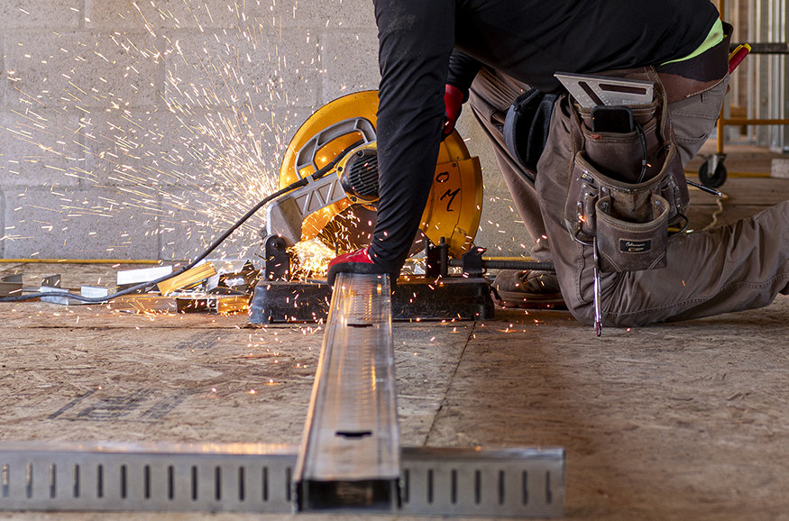 Construction crew cutting wall studs.