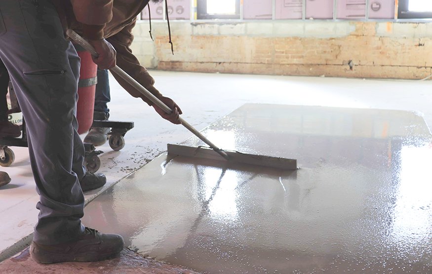 Self-leveling concrete spreading across interior floor.