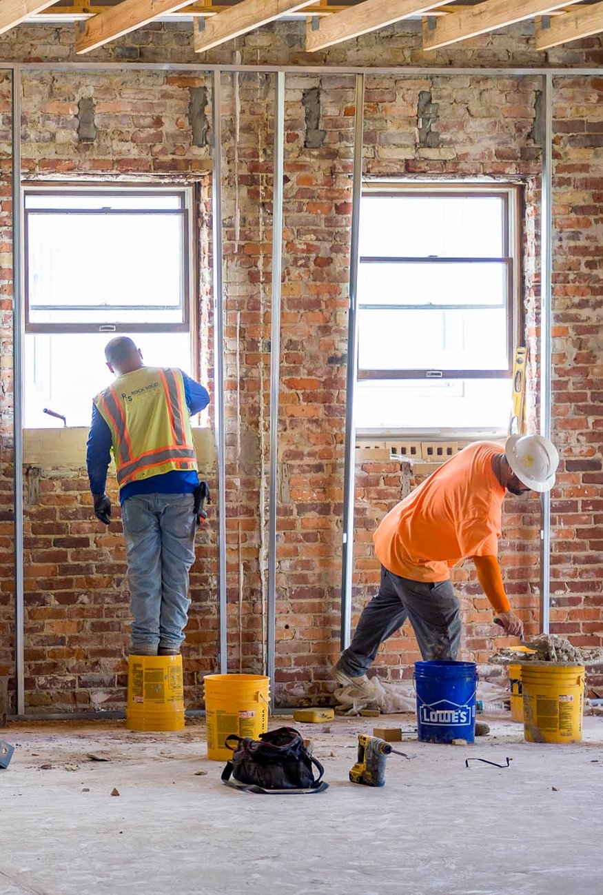 Masons restoring window openings on west wall.
