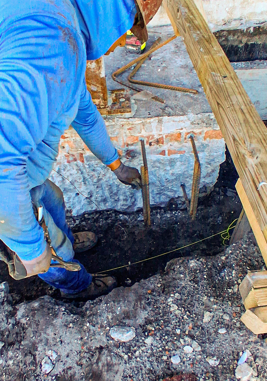 Worker positions reinforcing steel within existing foundation.