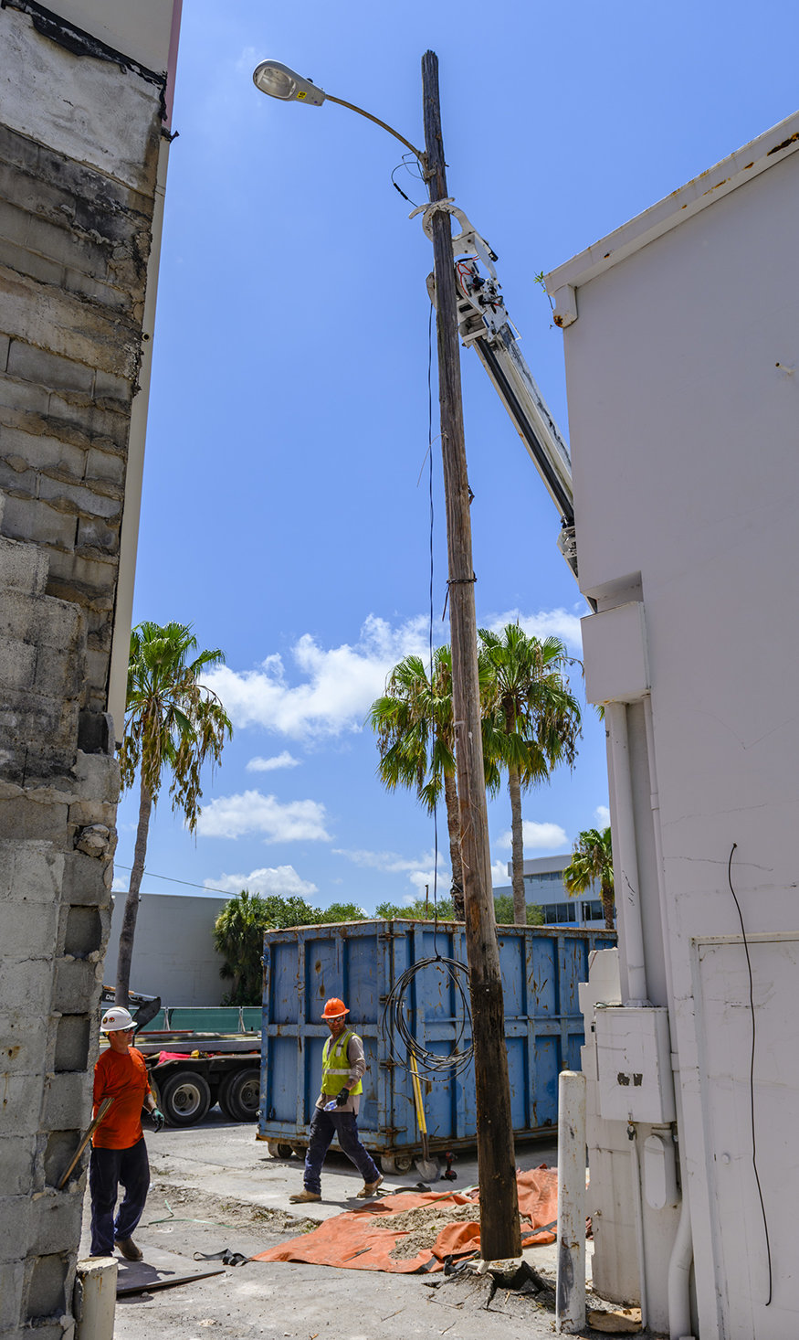 Close-up view of contractors working from a bucket truck to remove a utility light pole.