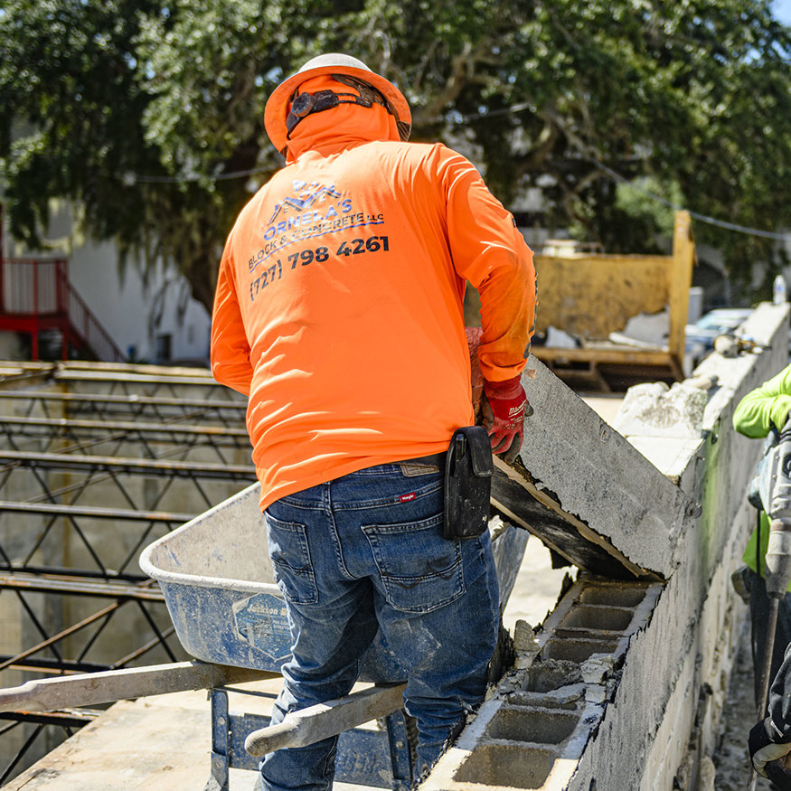 Workers use pry bars to loosen roofline masonry.