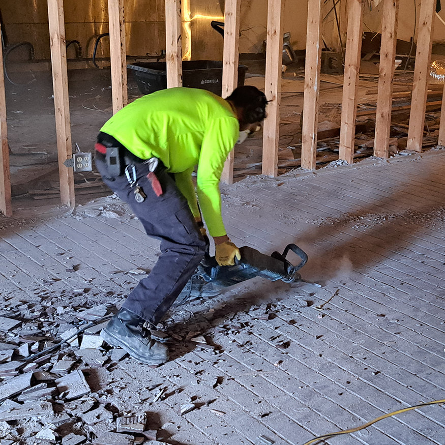 Crew member strips tile floor inside 623 Cleveland Street.