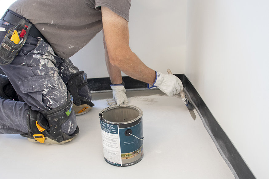 Crews apply concrete stain after patching and smoothing the floor surface.