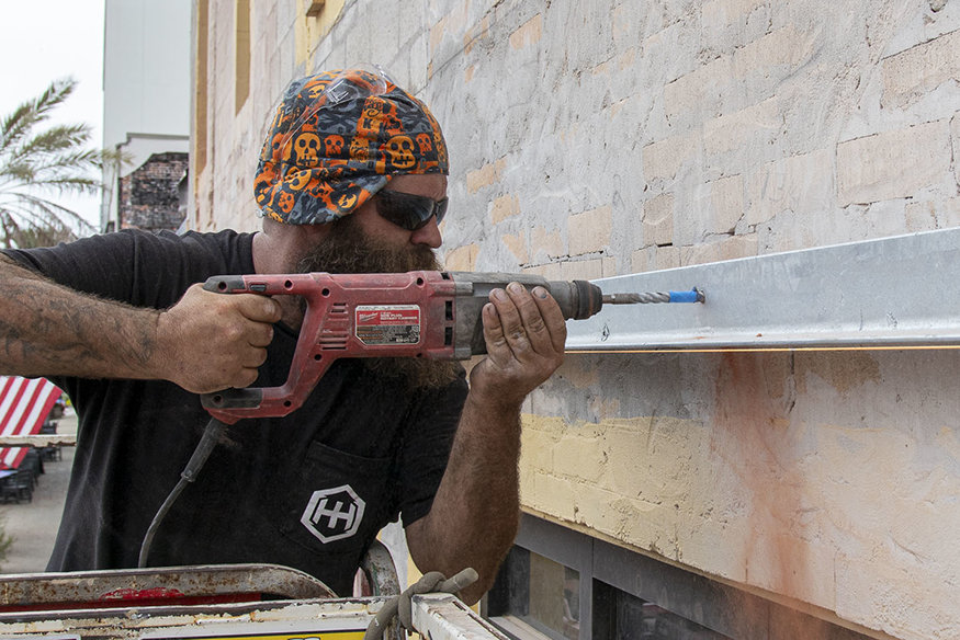 Worker drilling façade.