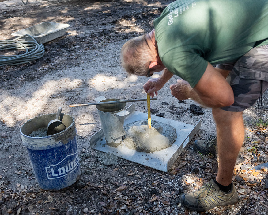 Worker conducts concrete slump test on fresh concrete.