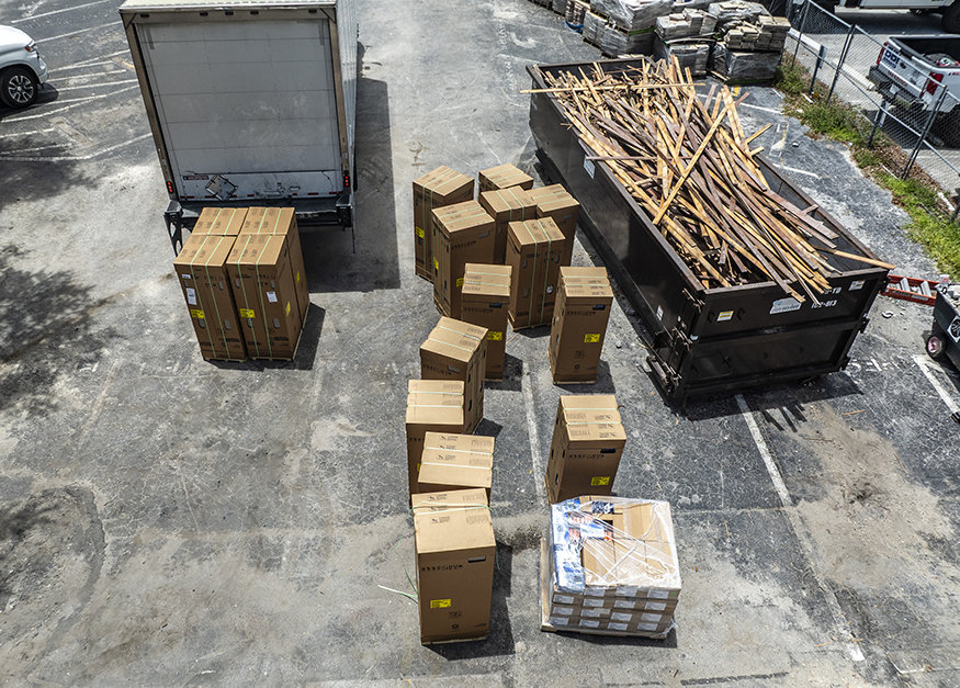 Staged A/C units and construction materials on site.