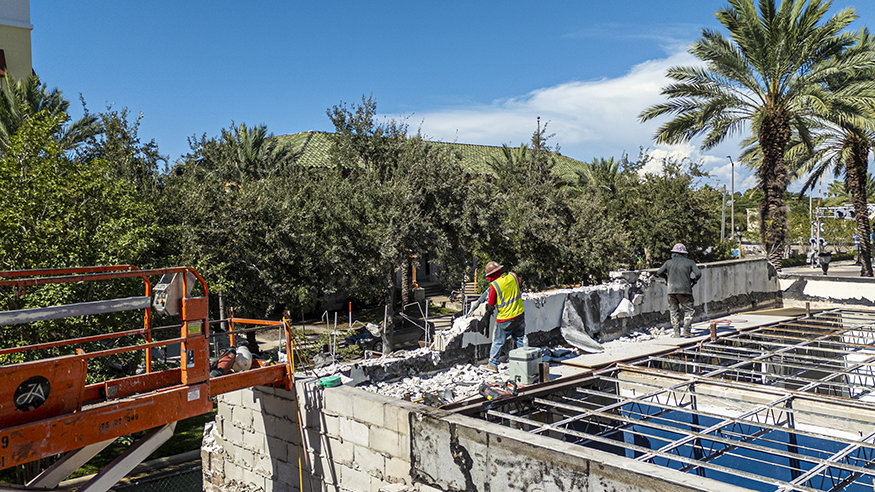 Crews remove canopy wall above exposed roof framing.