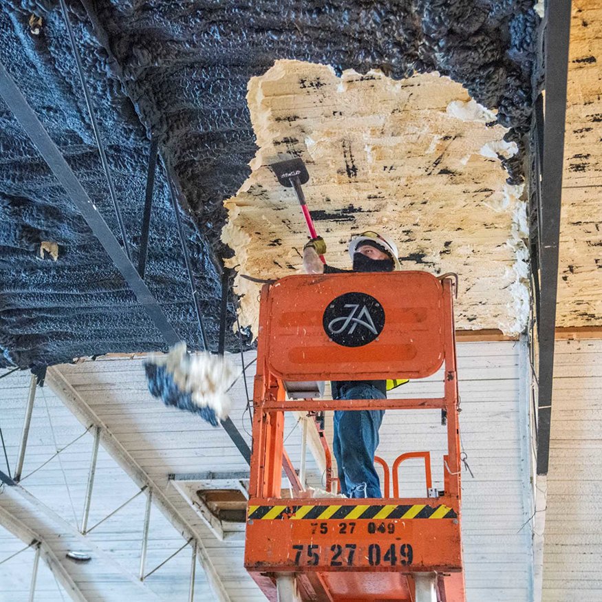 Scraping tool removing hardened insulation material.