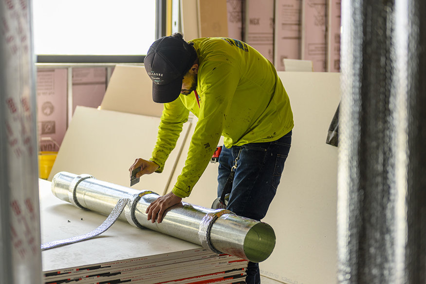Adding insulation to ductwork.