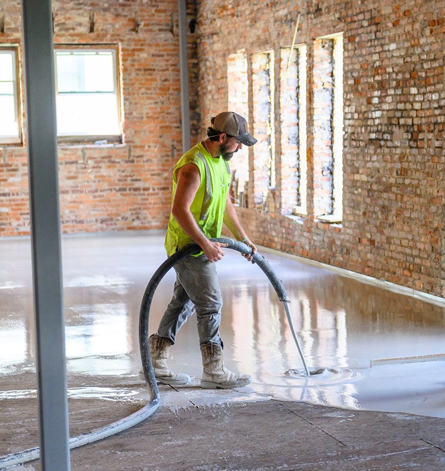 Worker inspecting the smooth concrete topping across floor.