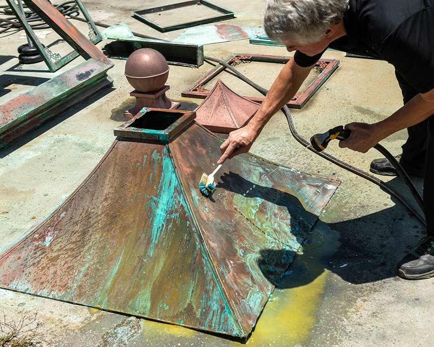 Applying patina treatment to historic clock copper.