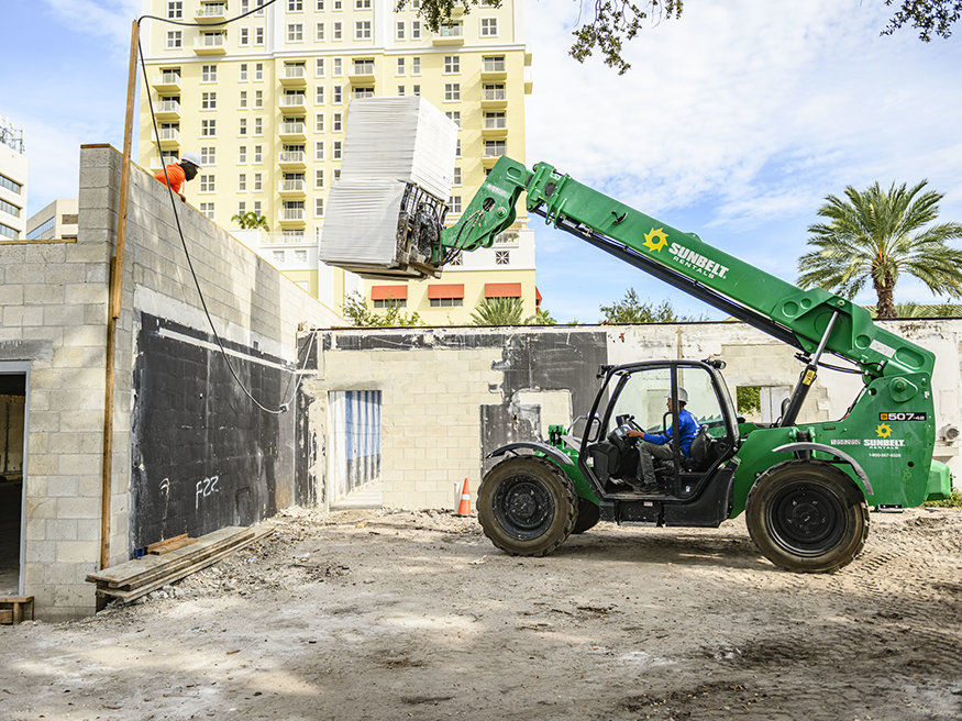 Telehandler lifts wrapped insulation pallet to roof deck.