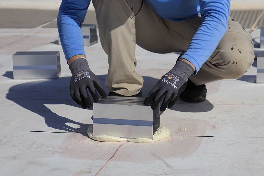 Securing brackets to the rooftop with adhesive.