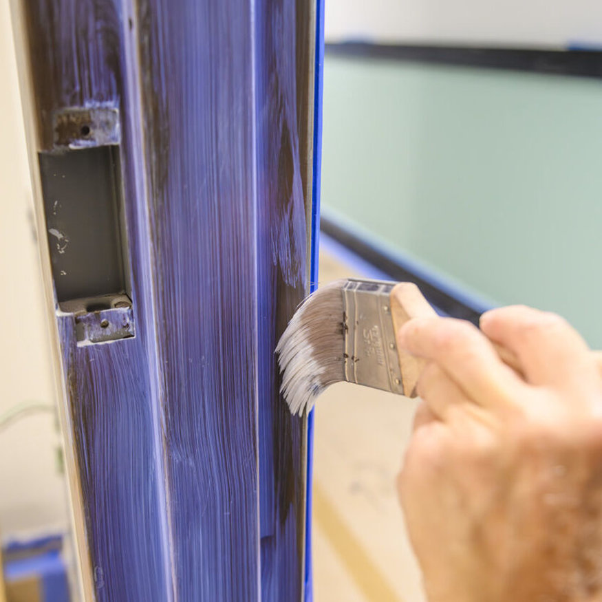 Close-up of finish being brushed onto door casing.