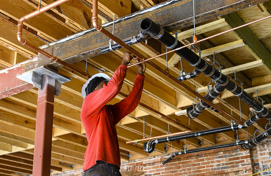 Worker connects copper pipe with press-fit fitting.