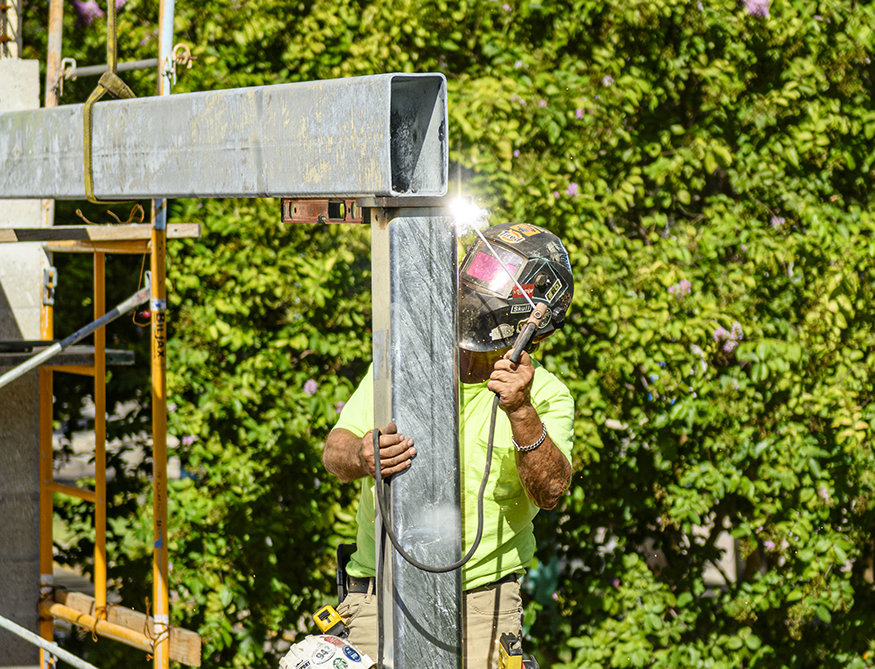 Welder secures steel beam connection.