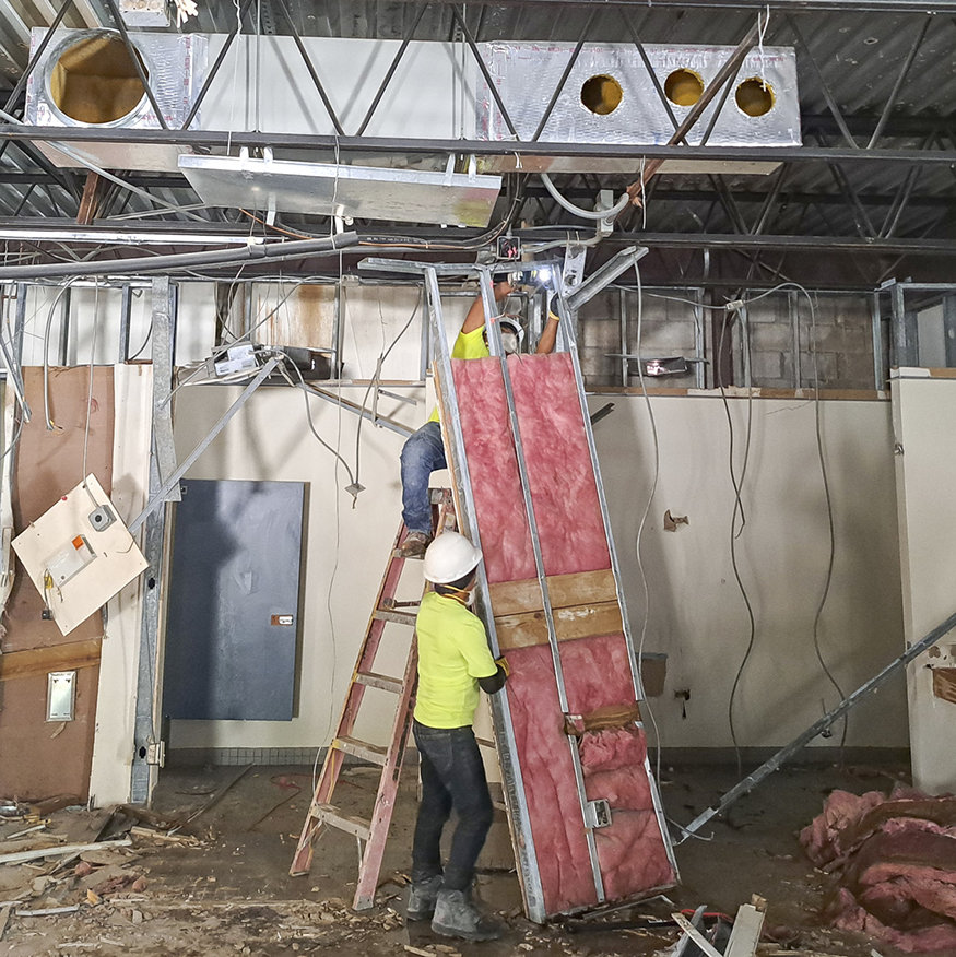 Crews remove a wall panel from the ceiling