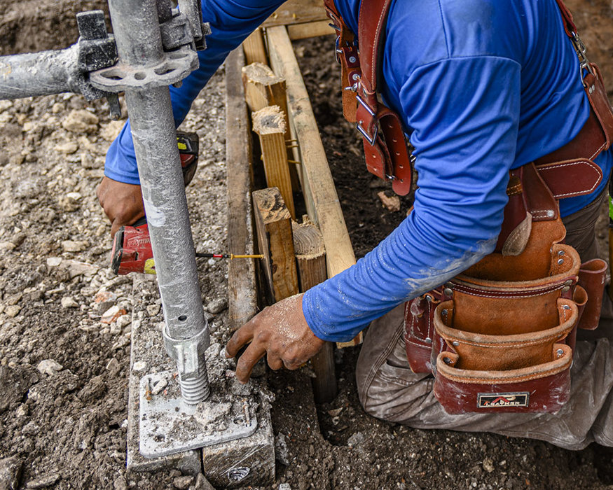 Worker secures wood footing form with cordless driver.