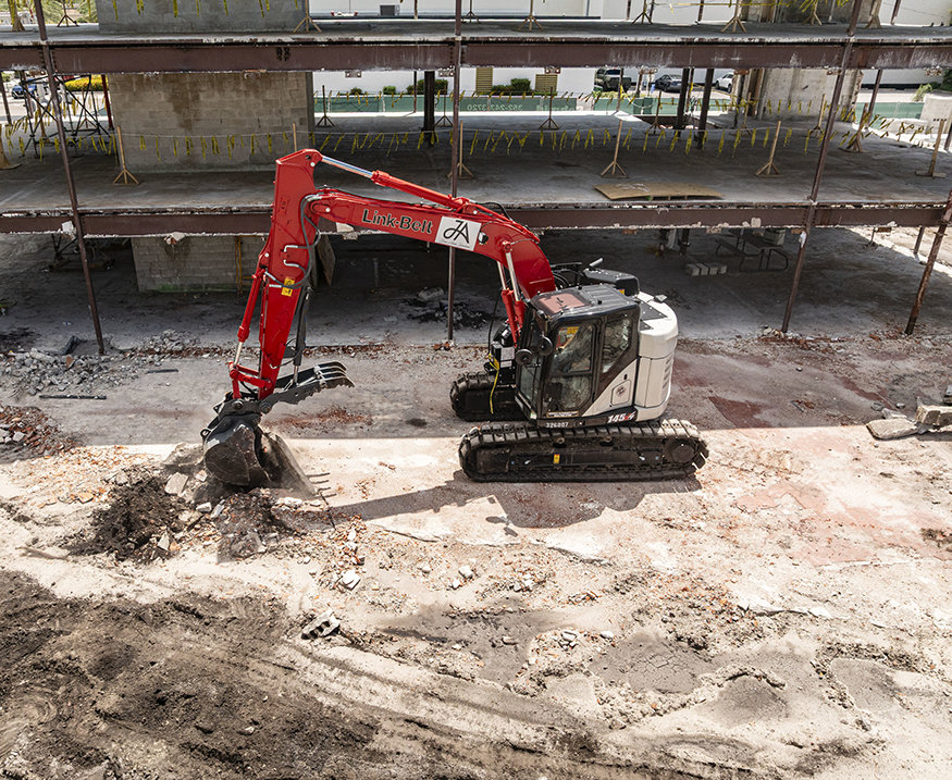 Excavator removes existing floor slab and tile.