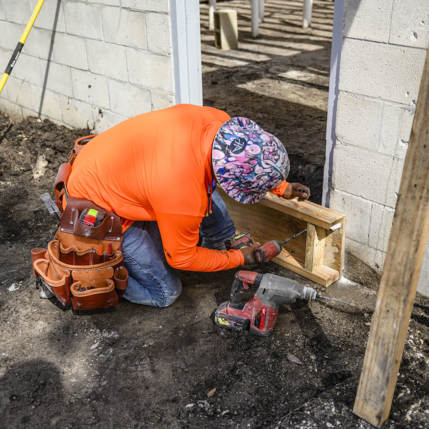 Worker fastens wood form at new door opening.