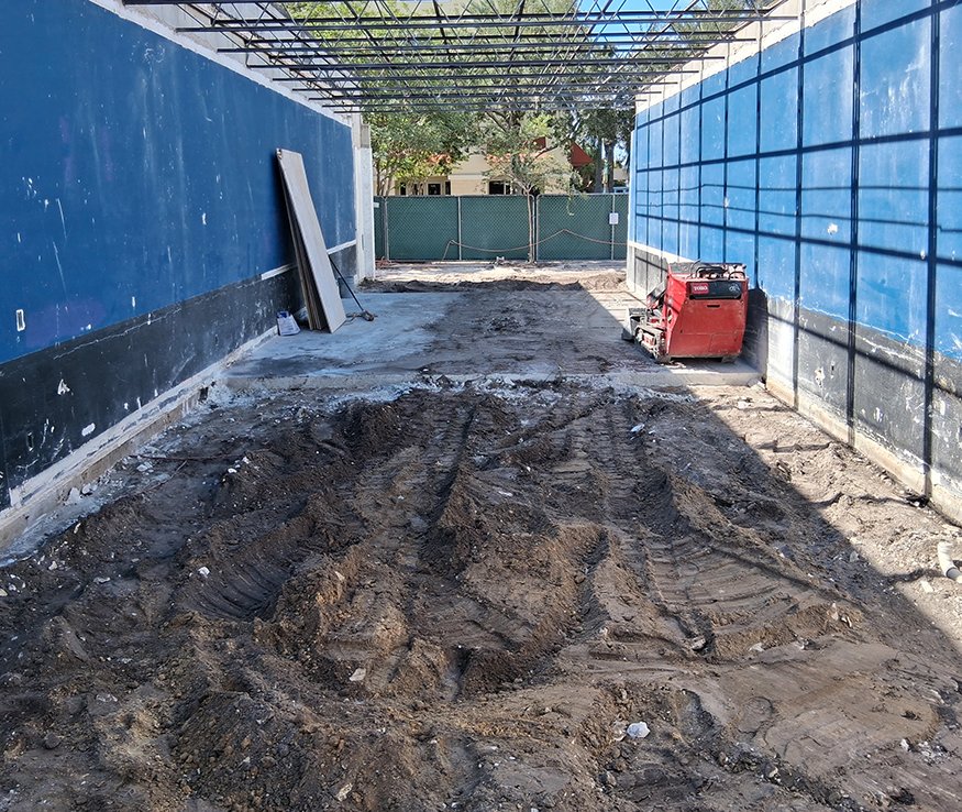 Excavated utility trench beneath former concrete floor.