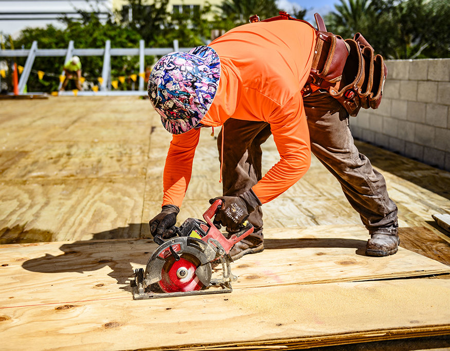 Worker cuts plywood for concrete beam formwork.