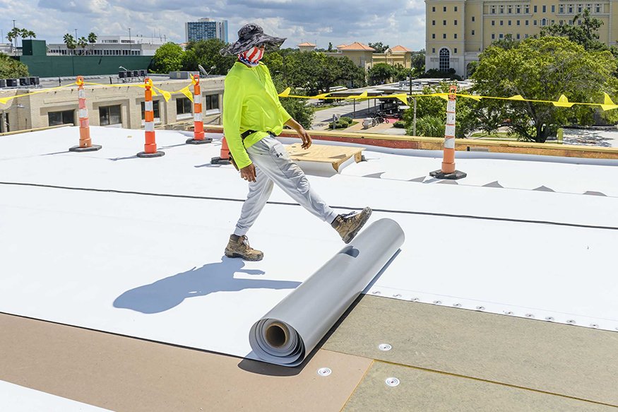 Large sheets are unrolled onto the roof.