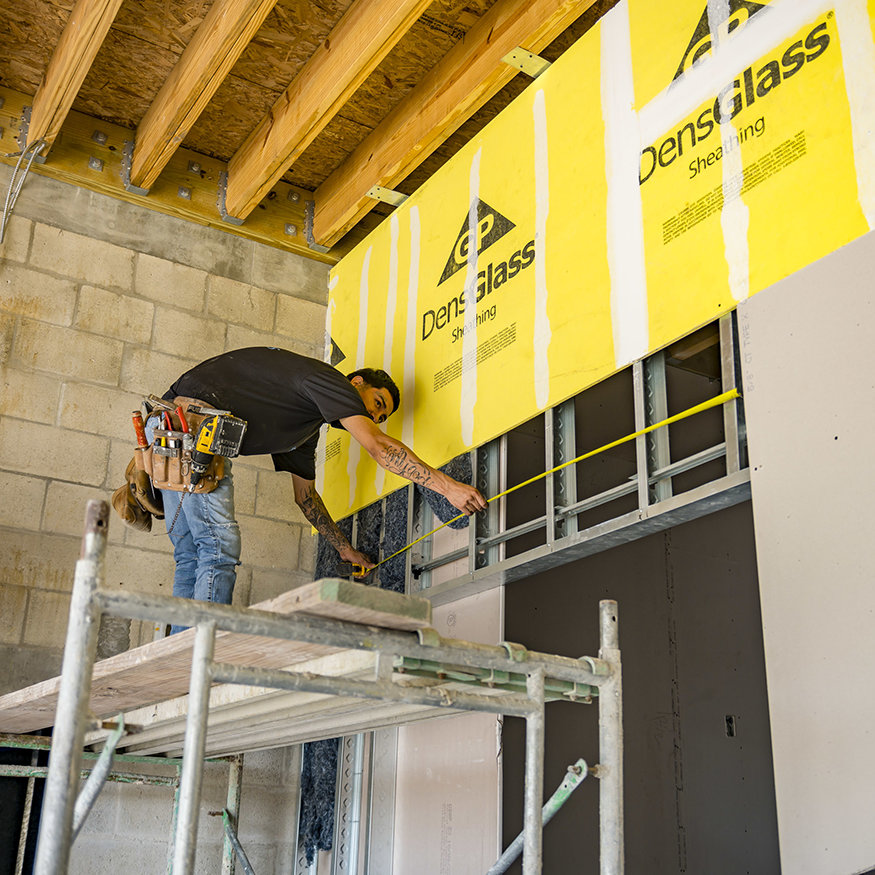 Measuring the drywall panels that form the interior walls.