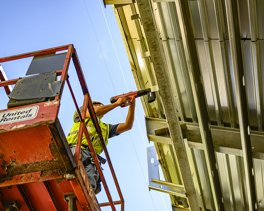 Worker fastens metal clip to structural framing.