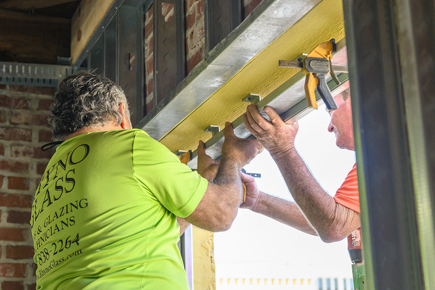 Crews install metal support brackets inside the west wall window openings.
