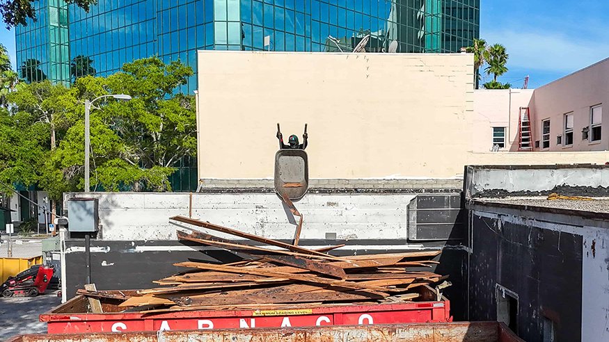 Removed roof decking fills a red construction dumpster.