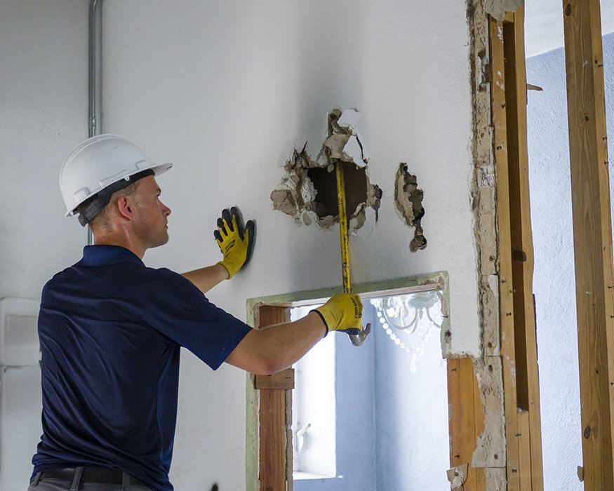 Close-up of demolition worker prying drywall from bathroom wall at 617 Cleveland.